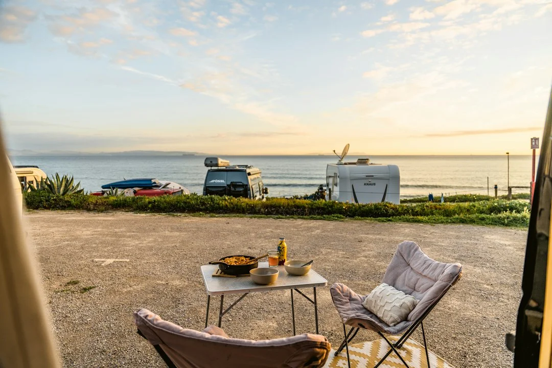 Mesa y sillas plegables en una zona de camping junto a una furgoneta camper